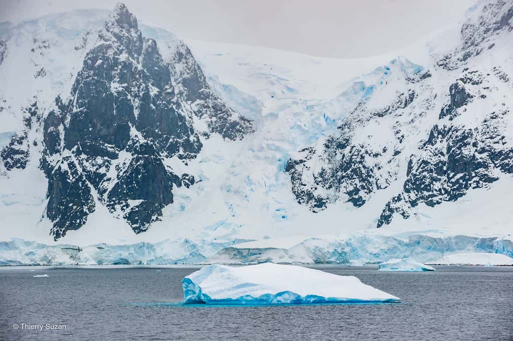 Les falaises imposantes du chenal Lemaire s’élèvent majestueusement au-dessus des eaux glacées, formant des barrières naturelles spectaculaires. Leur silhouette majestueuse, sculptée par les vents et les glaces, témoigne de la puissance brute de l'Antarctique. Chenal Lemaire © Thierry Suzan – Tous droits réservés